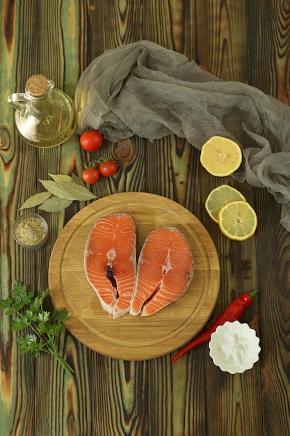 Bife de salmão fresco com ingredientes no fundo escuro de madeira