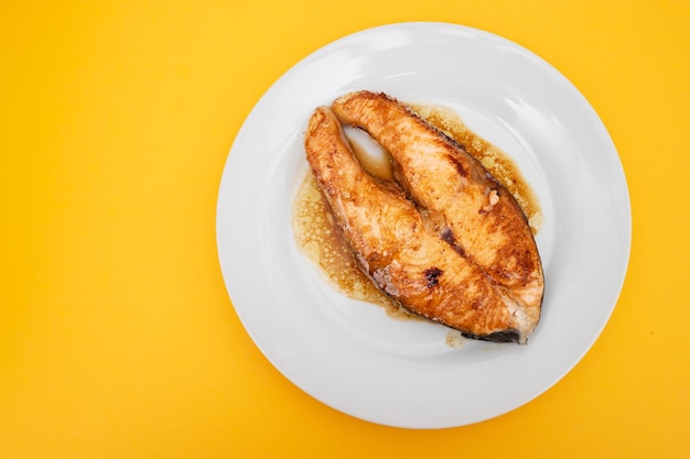 Foto bife de salmão frito com molho em prato pequeno branco