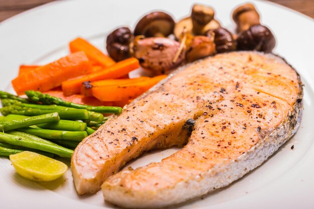 Foto bife de salmão grelhado com legumes em chapa branca para o jantar.