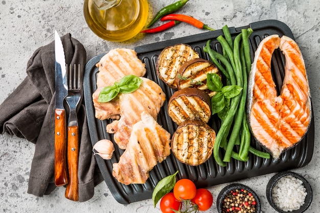 Bife de salmão grelhado, frango e vegetais sobre cinza