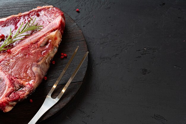 Bife de t-bone cru com alecrim, pimenta. Preparado para cozinhar. Fechar-se.