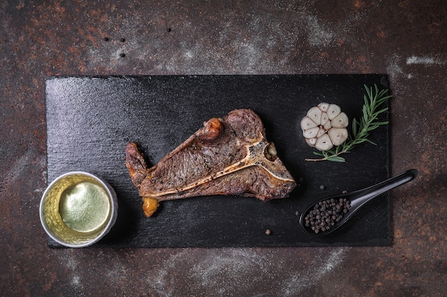 Bife de t-bone grelhado na chapa de ardósia preta e velha mesa de cozinha