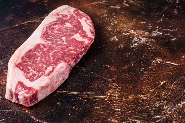 Bife de tira de Nova York cru ou striploin em uma mesa de açougueiro