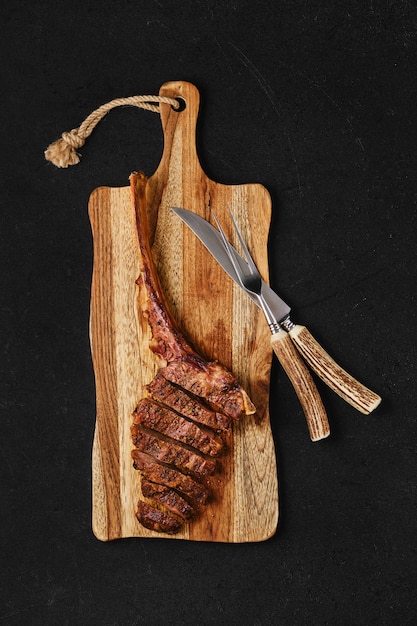 Bife de Tomahawk cortado em fatias na tábua de madeira