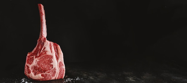 Bife de tomahawk de carne fresca na placa de madeira velha banner de fundo escuro