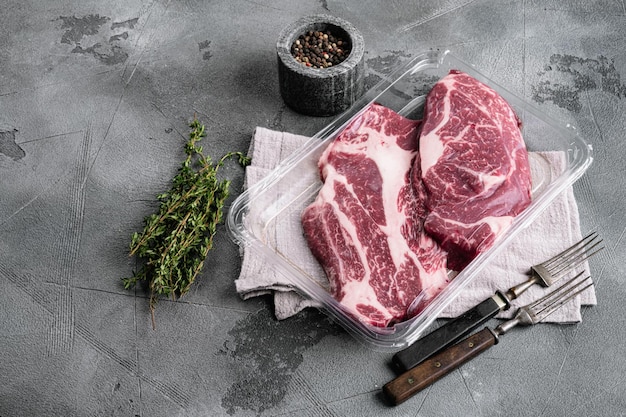 Bife de vaca em embalagem a vácuo. Conjunto de rolo de olho de Chuck do mercado, no fundo da mesa de pedra cinza, vista superior plana lay