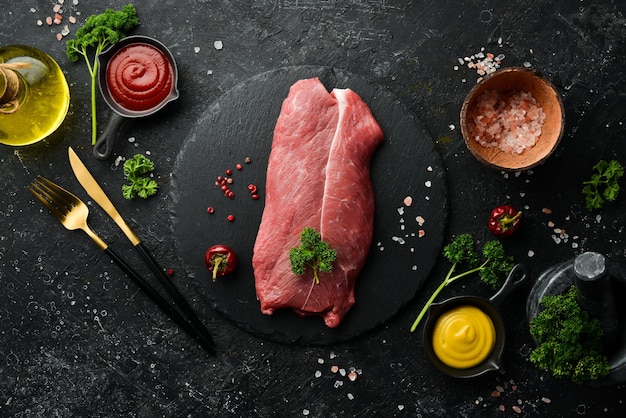 Bife de vitela bife orgânico de carne crua em fundo de pedra ardósia preta vista superior carne crua