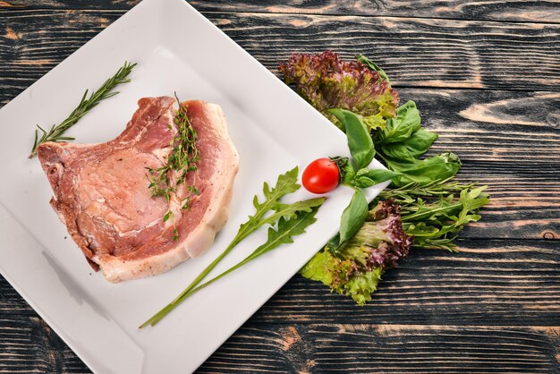 Bife de vitela cru em um prato Em um fundo de madeira Vista superior Espaço livre para texto