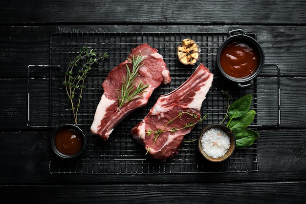 Bife de vitela cru no osso em um fundo de pedra preto Carne