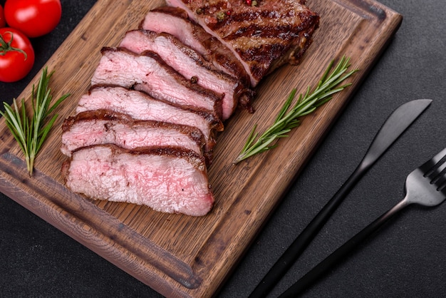 Foto bife delicioso suculento fresco em uma superfície escura. prato de carne com especiarias e ervas