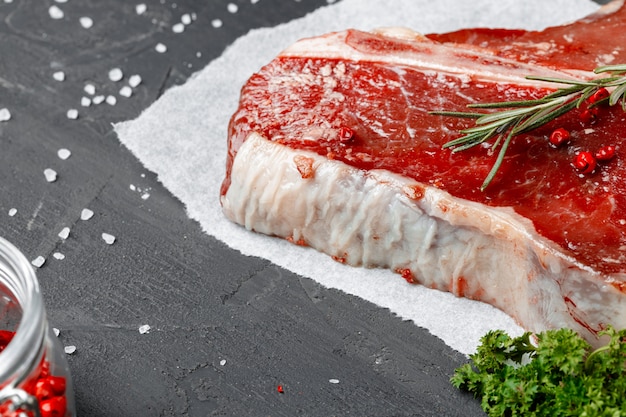 Bife do lombo cru de carne fresca com especiarias em um fundo escuro, close-up