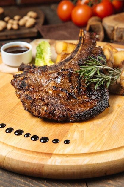 Foto bife em uma tábua de madeira com batatas