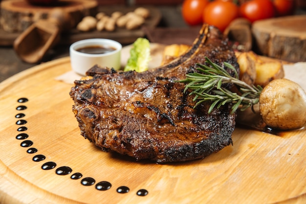 Bife em uma tábua de madeira com batatas