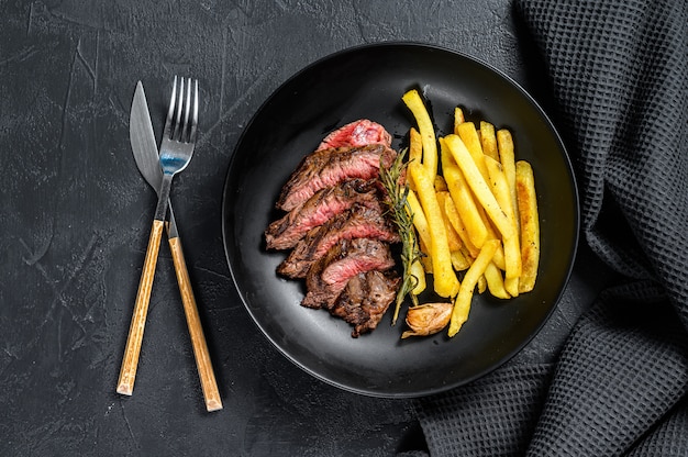 Bife fatiado com batatas fritas e carne marmorizada. Vista do topo