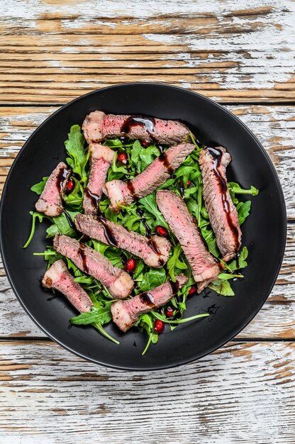 Bife fatiado grelhado com salada de folhas de rúcula.