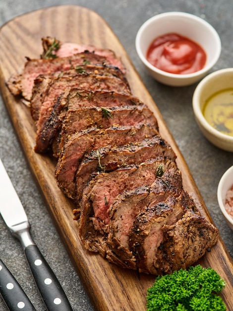 Bife fatiado grelhado na tábua sobre mesa cinza Chuck filé mignon