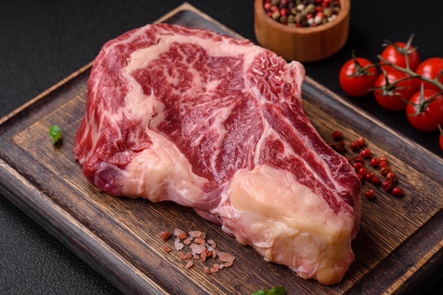 Bife fresco e suculento de carne crua com sal e especiarias sobre um fundo escuro de concreto