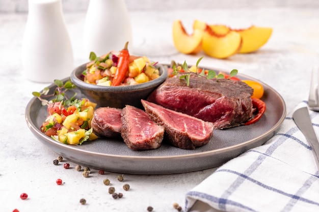 Bife frito com molho de pêssego, tomate e pimenta. bife frito médio ou raro cortado em pedaços. pronto para comer. fechar-se.