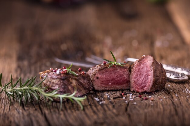 Bife grelhado com alecrim, sal e pimenta na velha tábua. Bife de filé mignon.