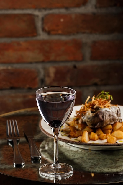 Bife grelhado com batatas douradas assadas servidas com cebola crocante em cima sobre um fundo de tijolos receita deliciosa