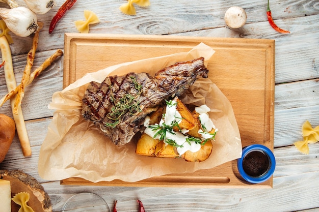 Bife grelhado com batatas na tábua de madeira