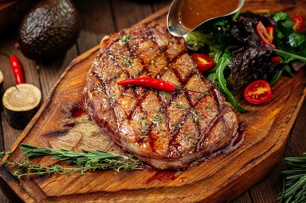 Bife grelhado com salada e molho no fundo de madeira