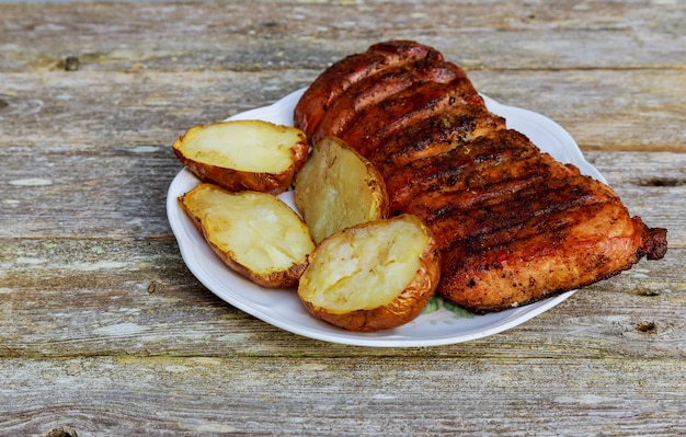 Bife grelhado do roubo com a batata roasted na placa sobre a tabela de madeira.