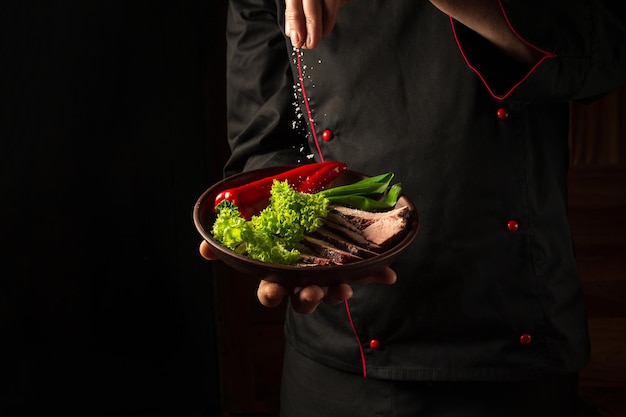 Bife grelhado e fatiado com legumes grelhados servidos no prato nas mãos do chef