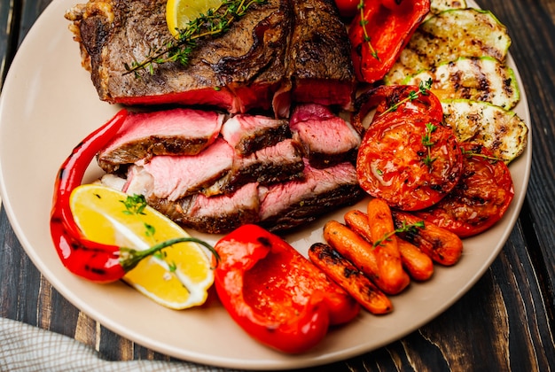 bife grelhado e legumes grelhados em um prato na madeira