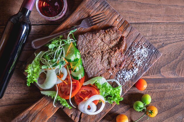 Bife grelhado e sal em uma tábua de madeira