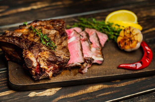 bife grelhado na tábua com limão, pimenta vermelha, alho e tempero no escuro rústico