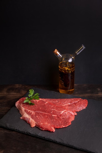 Bife minuto cru de carne marmorizada em garrafa de ardósia com óleo vegetal e vinagre balsâmico