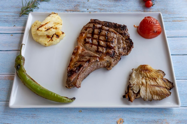 Bife no fundo azul de madeira com tomate assado, cebola e pimentão