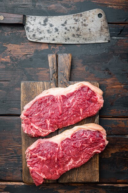 Bife striploin, corte de açougue de carne crua, na velha mesa de madeira