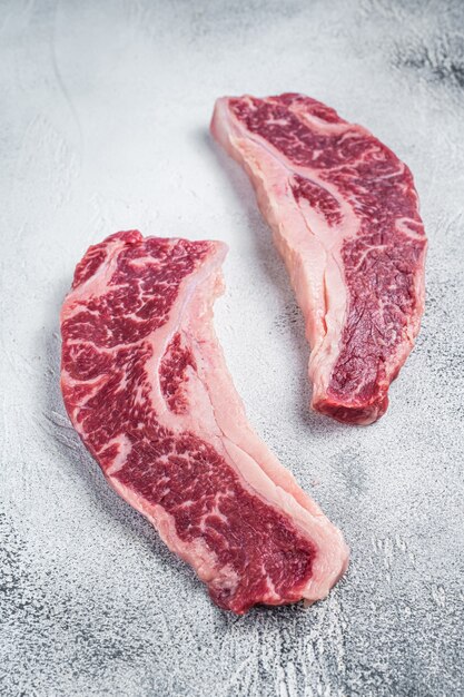 Bife striploin ou bife new york, corte de carne bovina crua de talho. fundo branco. vista do topo.