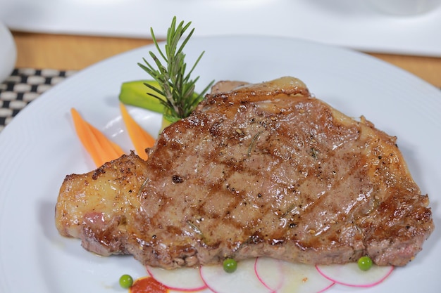 Bife suculento carne mal passada com salada verde no prato branco sobre a mesa pronta para comer