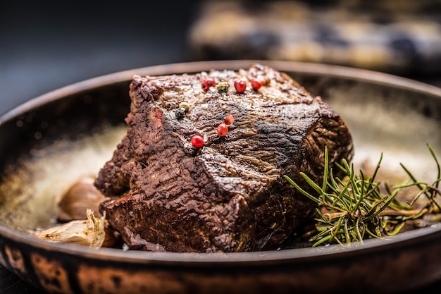 Bife suculento com especiarias e ervas na frigideira velha.