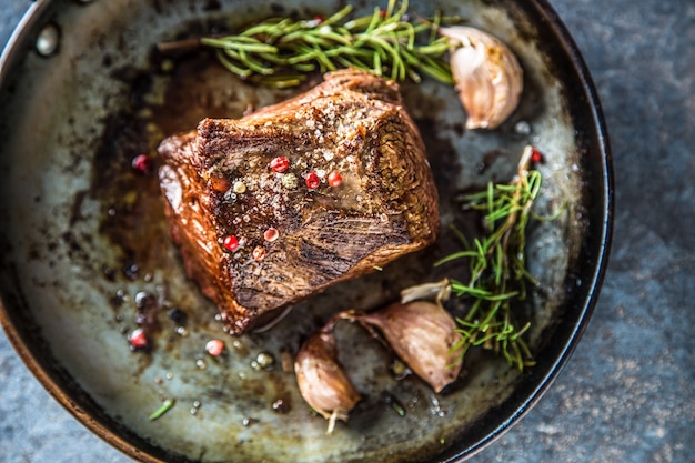 Bife suculento com especiarias e ervas na velha panela - topo da vista.