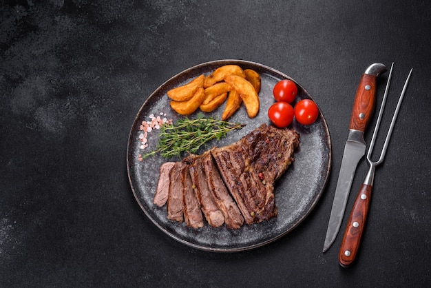 Bife suculento delicioso com especiarias e ervas em um fundo escuro de concreto. Pratos grelhados