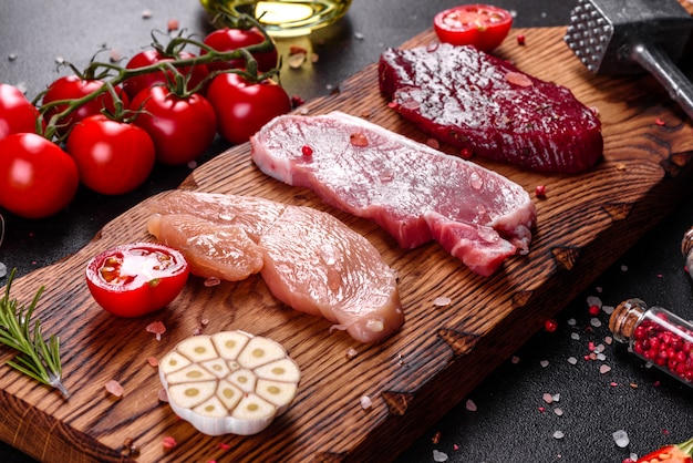 Bife suculento fresco de carne, porco e frango com legumes prontos para cozinhar. Bifes de diferentes variedades de carne preparados para cozinhar