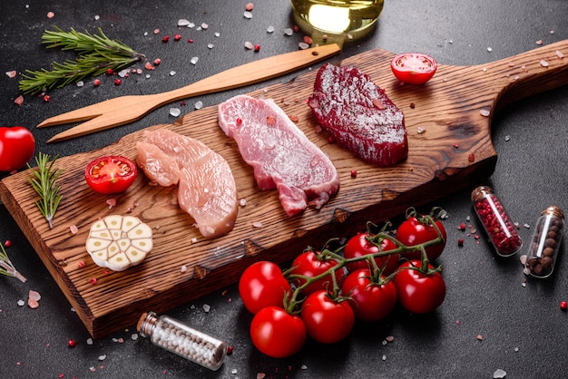 Bife suculento fresco de carne, porco e frango com legumes prontos para cozinhar. Bifes de diferentes variedades de carne preparados para cozinhar