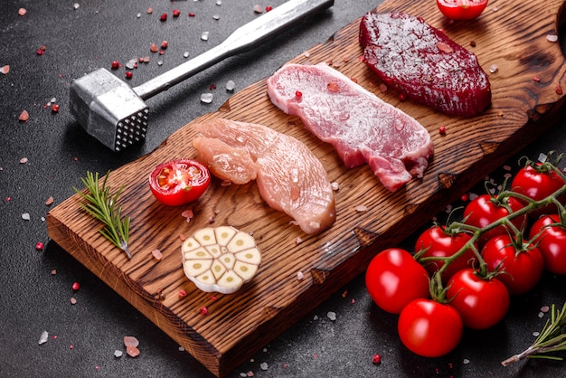 Bife suculento fresco de carne, porco e frango com legumes prontos para cozinhar. Bifes de diferentes variedades de carne preparados para cozinhar