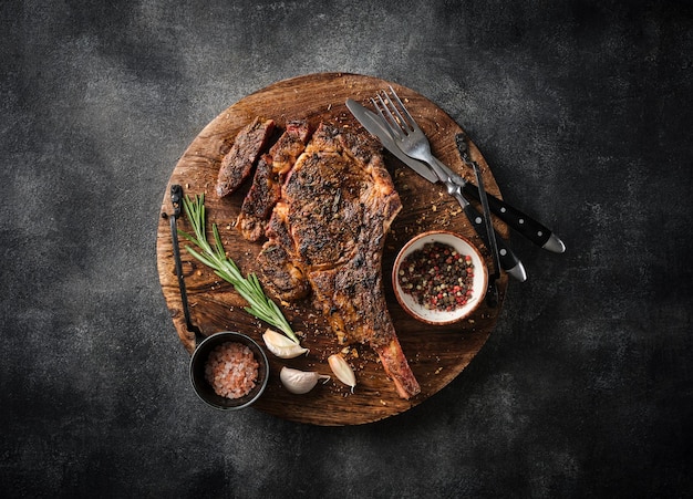 Bife Tomahawk recém-grelhado em uma tábua de madeira para churrasco comida vista superior fundo cinza
