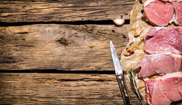 Bifes de carne crua com especiarias no fundo de madeira