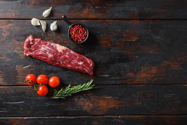 Bifes de carne crua e ervas em fundo de madeira