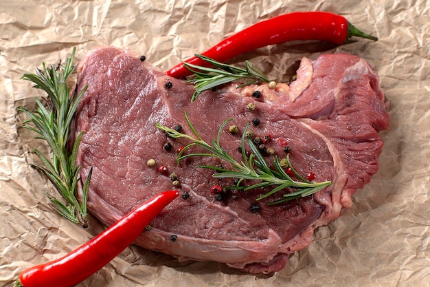 Bifes de carne crua em um pergaminho de cozinha com ingredientes para cozinhar carne