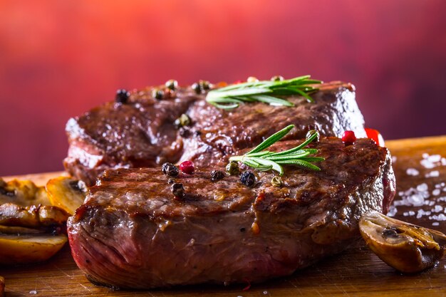 Bifes de carne crua na placa de madeira com especiarias e ervas.