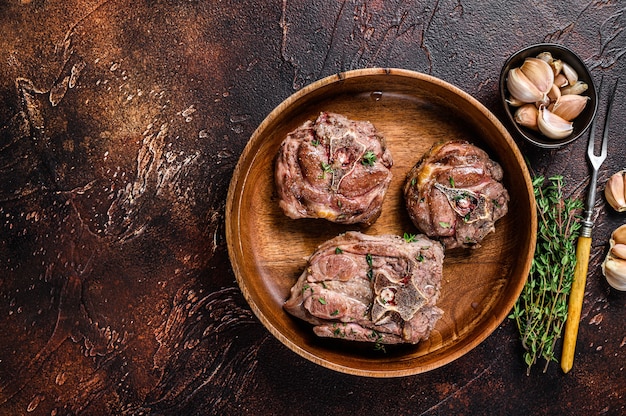 Bifes de carne de pescoço de cordeiro frito em uma placa de madeira com ervas.