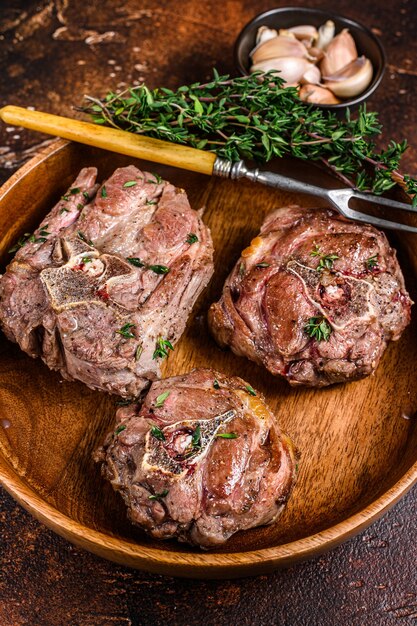 Bifes de carne de pescoço de cordeiro frito em uma placa de madeira com ervas.