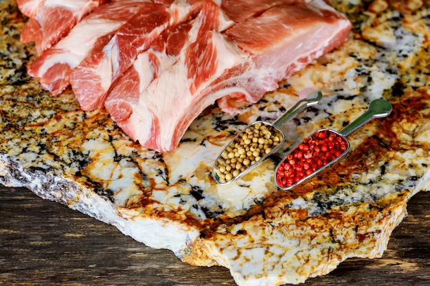 Bifes de carne de porco crua na placa de madeira com ervas